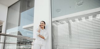 the girl is standing at the window with the blinds closed