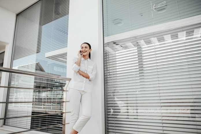 the girl is standing at the window with the blinds closed