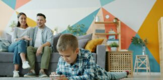 boy-plays-on-phone-while-parents-watch-from-couch