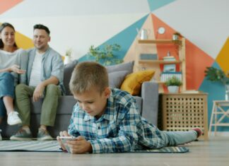 boy-plays-on-phone-while-parents-watch-from-couch